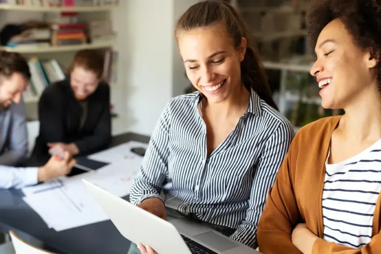 Marketing team collaborating and reviewing strategies on a laptop in a modern office